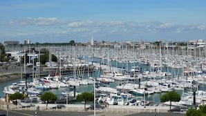 Un port de plaisance rempli de nombreux bateaux, un ciel dégagé et une vue lointaine sur la ville.