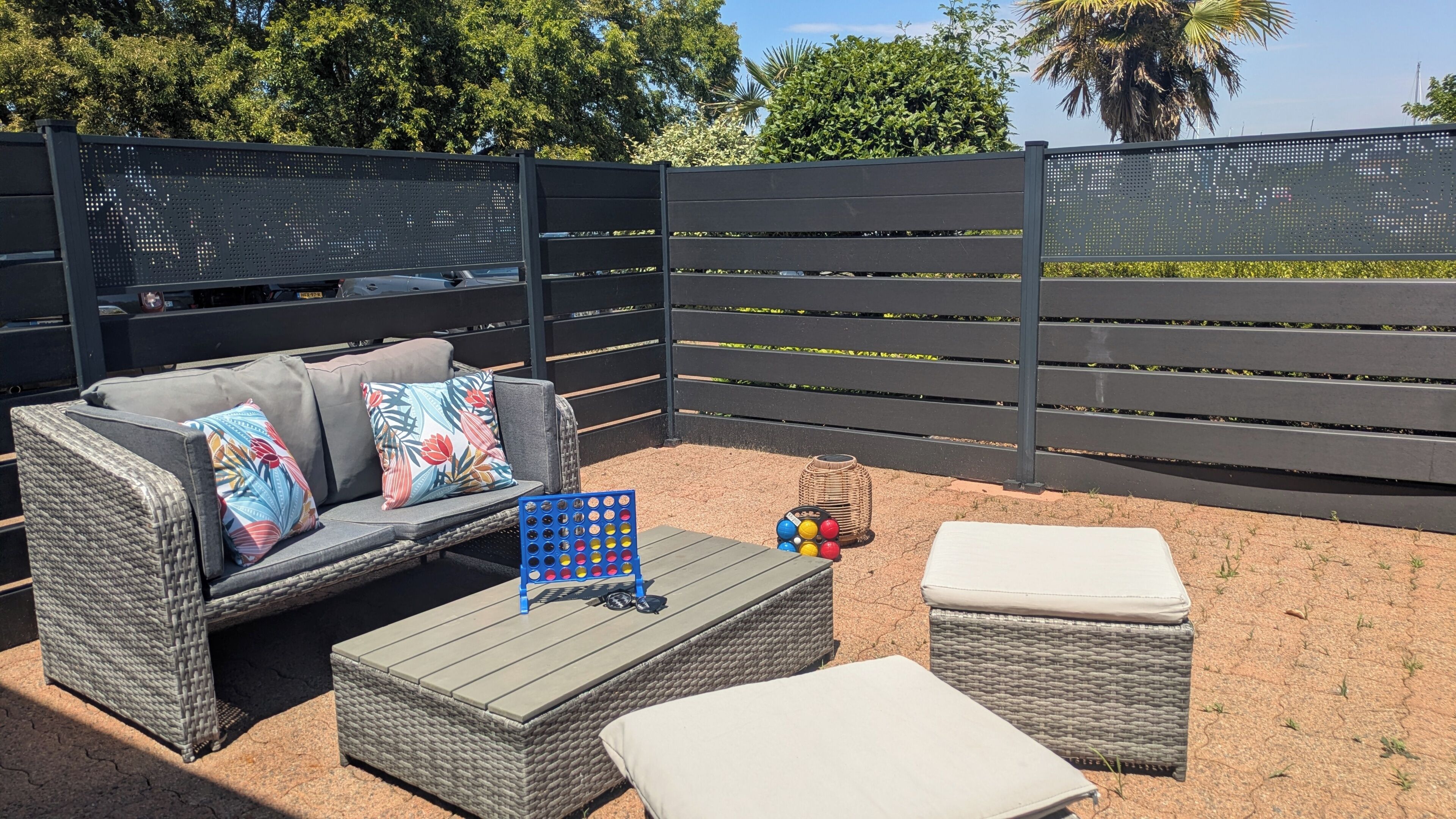 An outdoor seating area with a sofa, ottoman, and a small table with a board game.