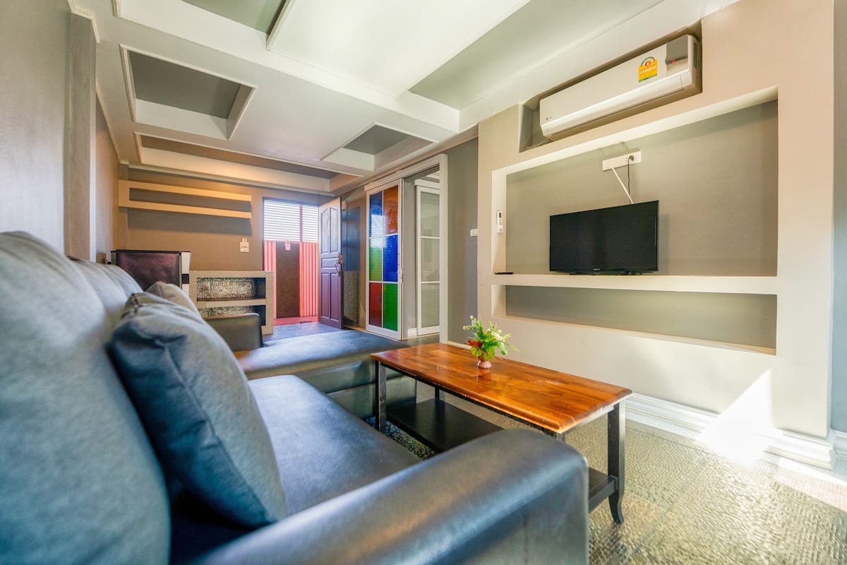 A modern living room with a sofa, a coffee table, and a TV on a shelf.