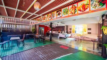 An indoor dining area with wooden flooring, tables, and chairs.