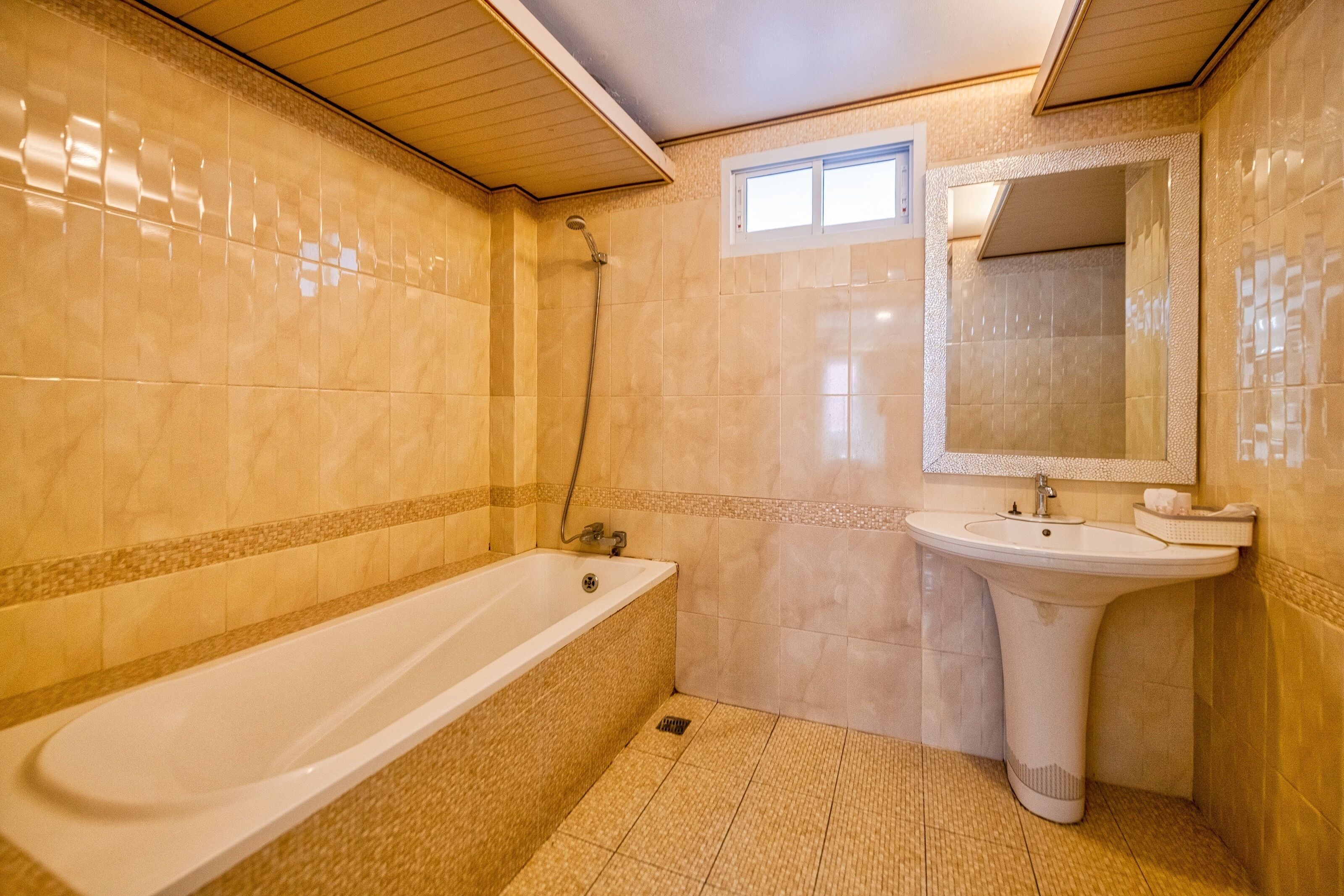 A bathroom with a bathtub, sink, and mirror.
