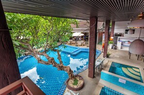 A pool area with a tree, lounge chairs, and a covered seating area. - The Train Resort - Your Relaxing Resort with Large Pool & Jacuzzi (Pattaya)