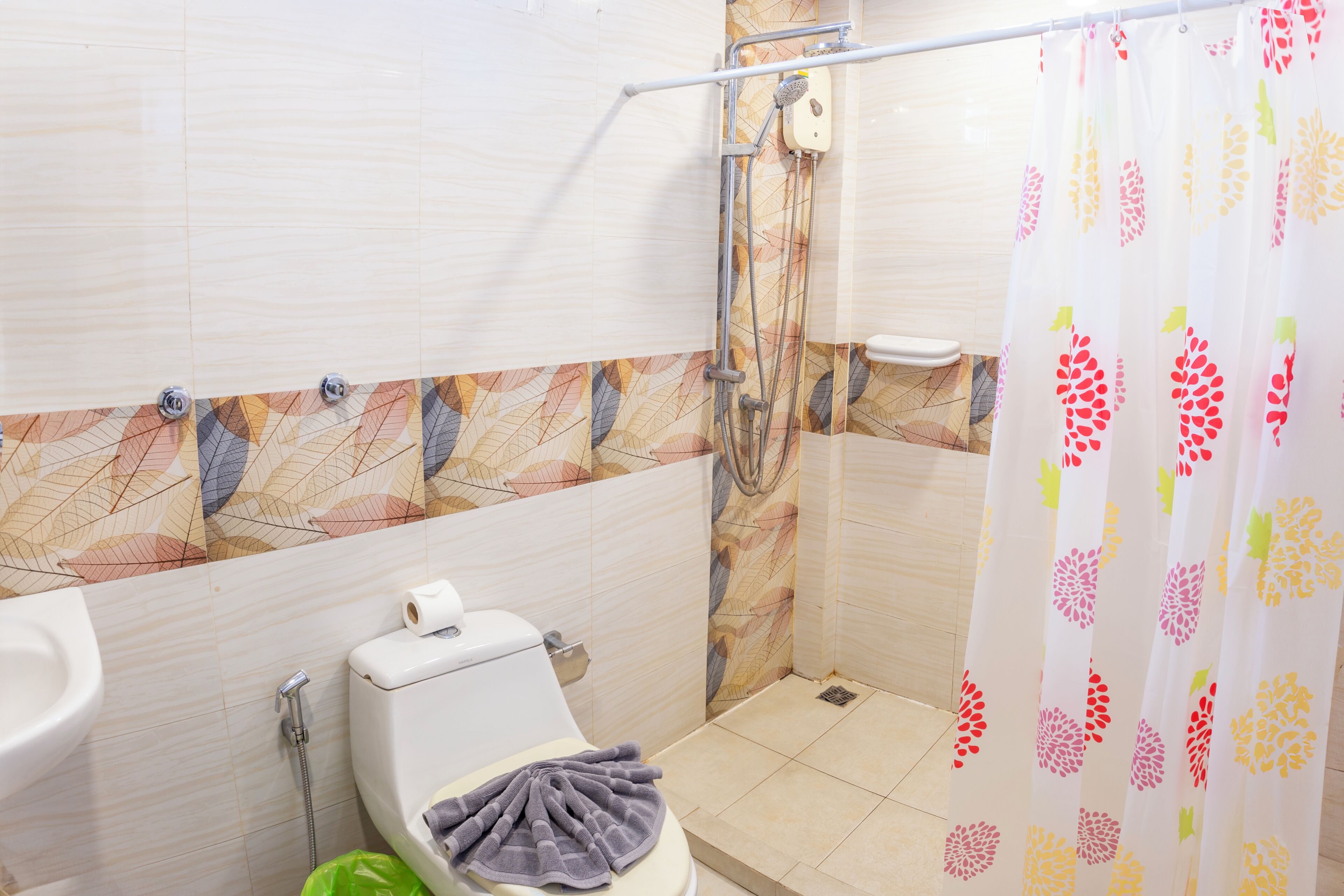 A bathroom with a toilet, shower, and a towel on the seat.