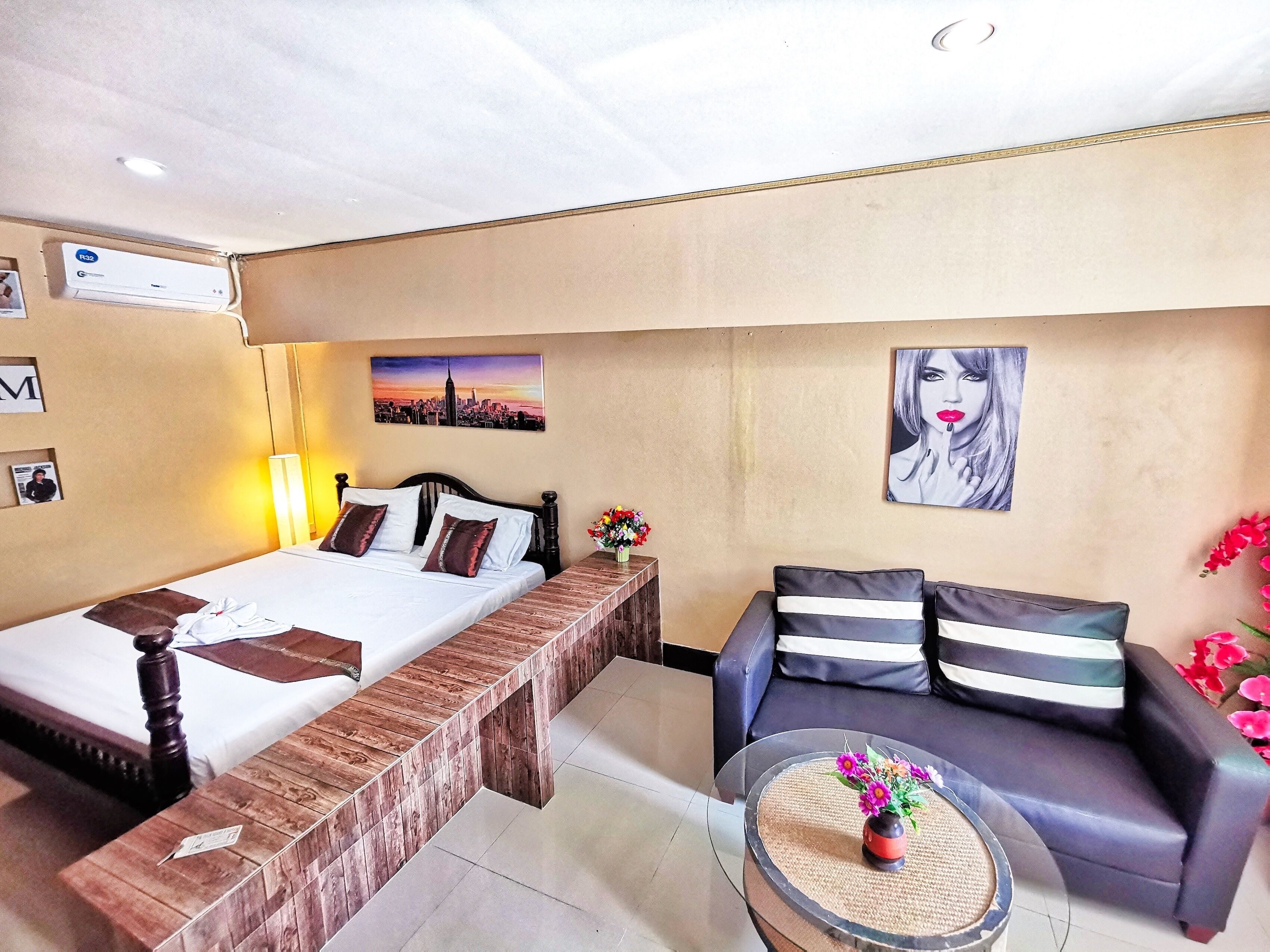 A hotel room with a bed, a sofa, a coffee table, and a wall-mounted air conditioner.
