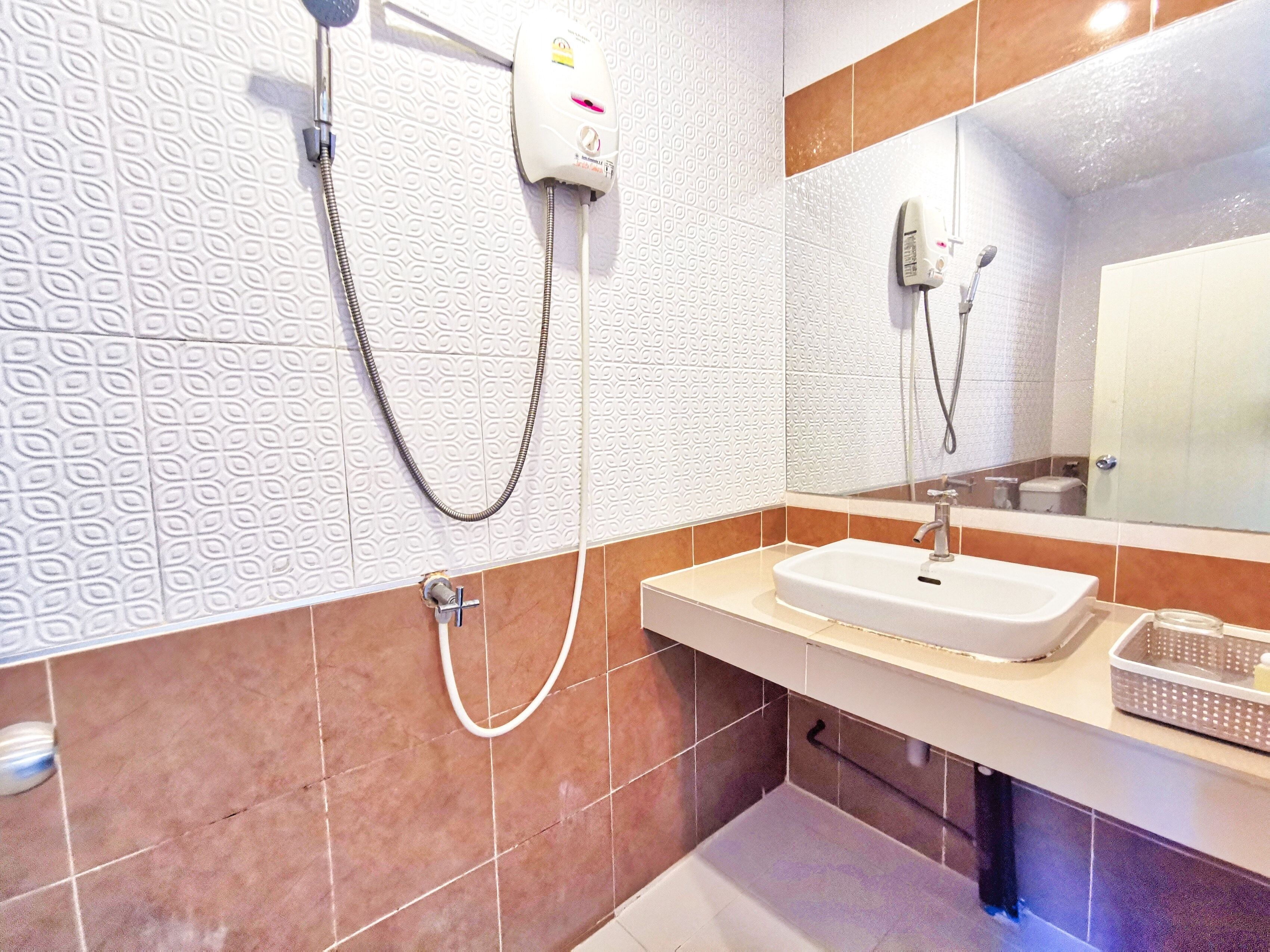A bathroom with a white textured wall, a beige countertop, a sink, a mirror, and a shower with a handheld showerhead.