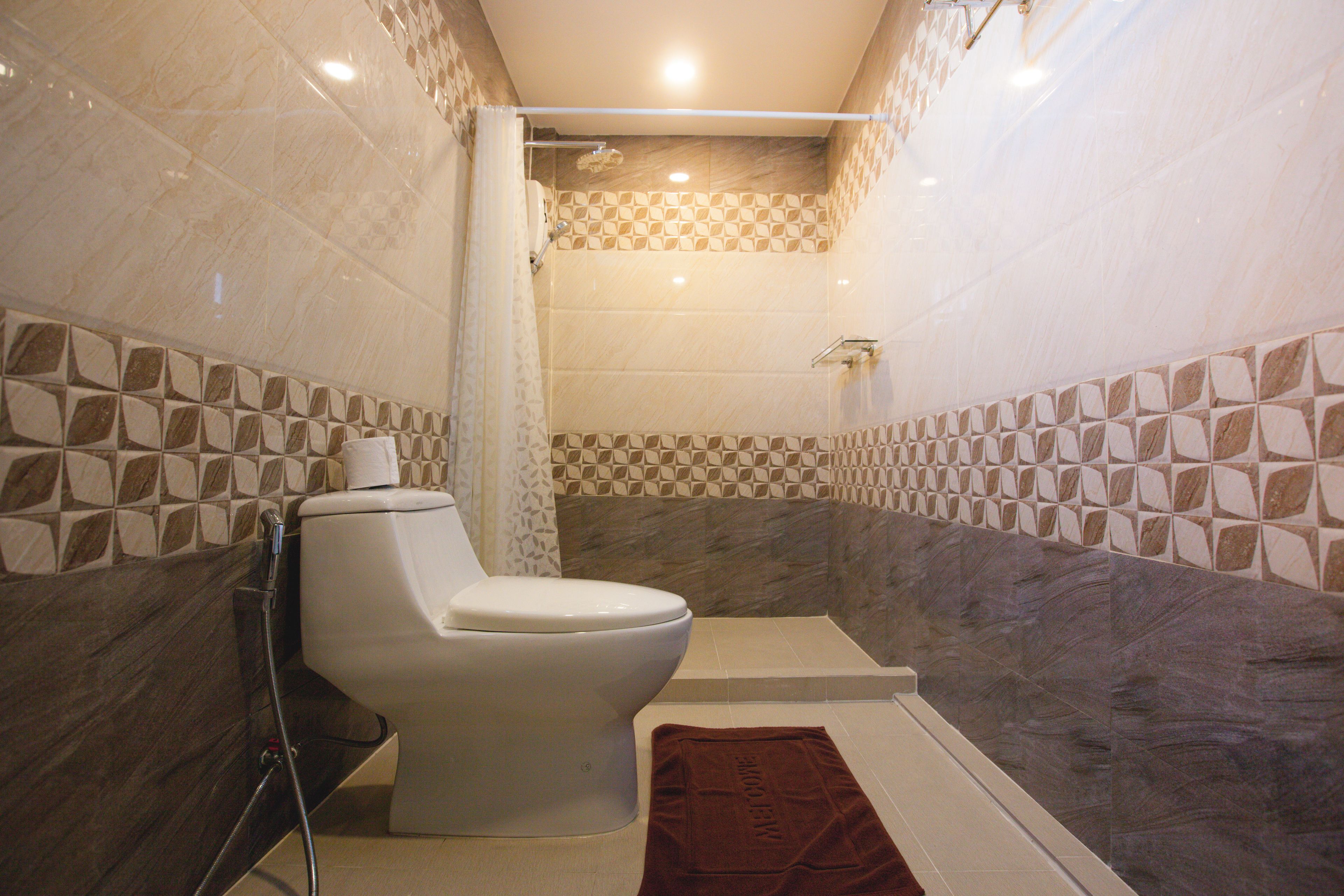 A bathroom with a toilet, shower, and tiled walls.