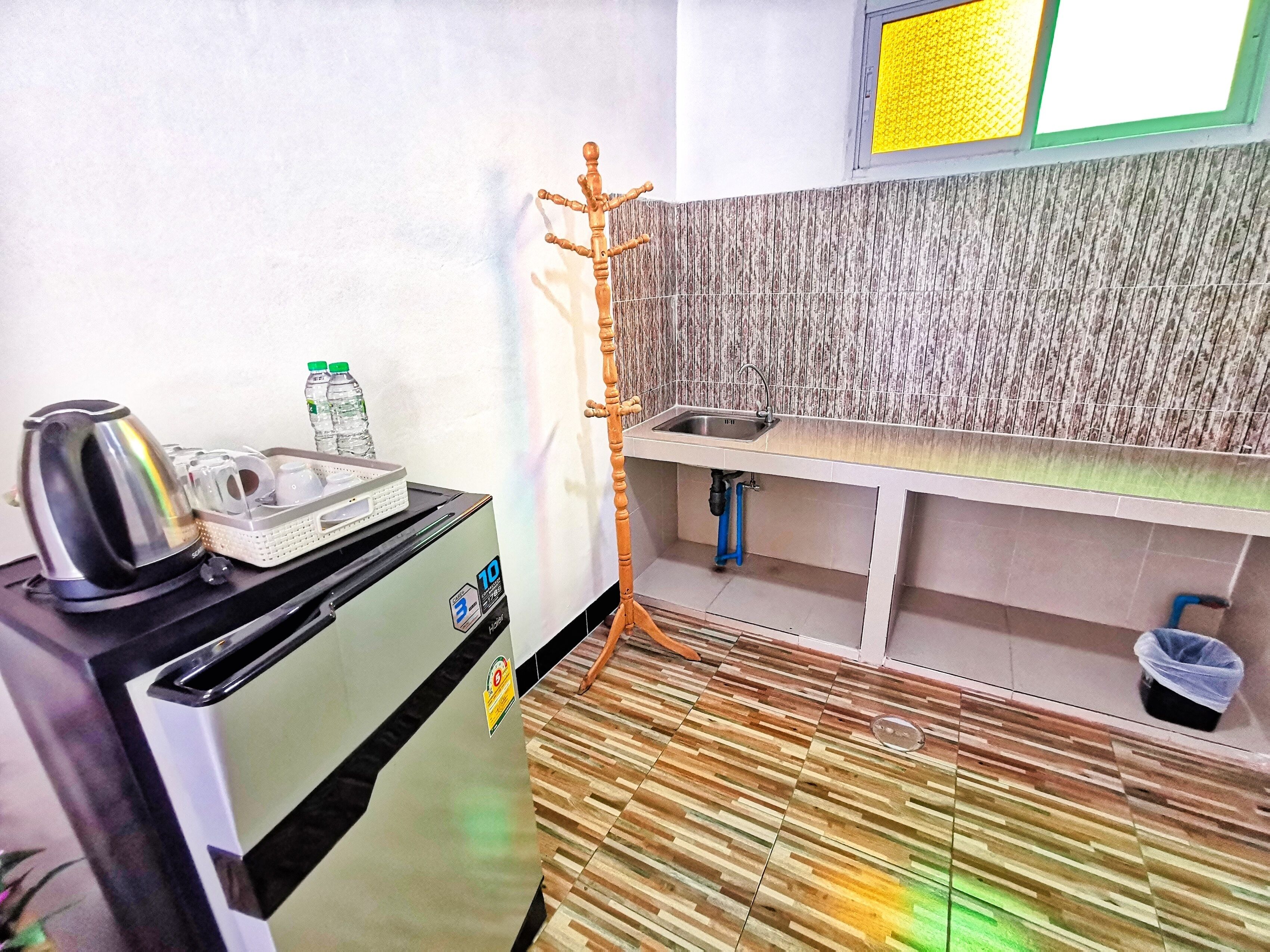 A compact kitchenette with a microwave, kettle, and water bottles on the counter.