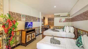 Habitación de hotel con dos camas, un televisor, una planta en maceta y un baño visible al fondo.