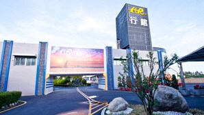 A modern building with a large billboard advertising a tour. - Yudali HR Motel (Donggang)