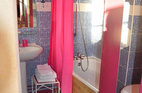 A bathroom with a sink, a shower, and a mirror.