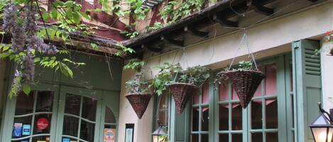 Un patio con una mesa y sillas, plantas en macetas y cestas colgantes.