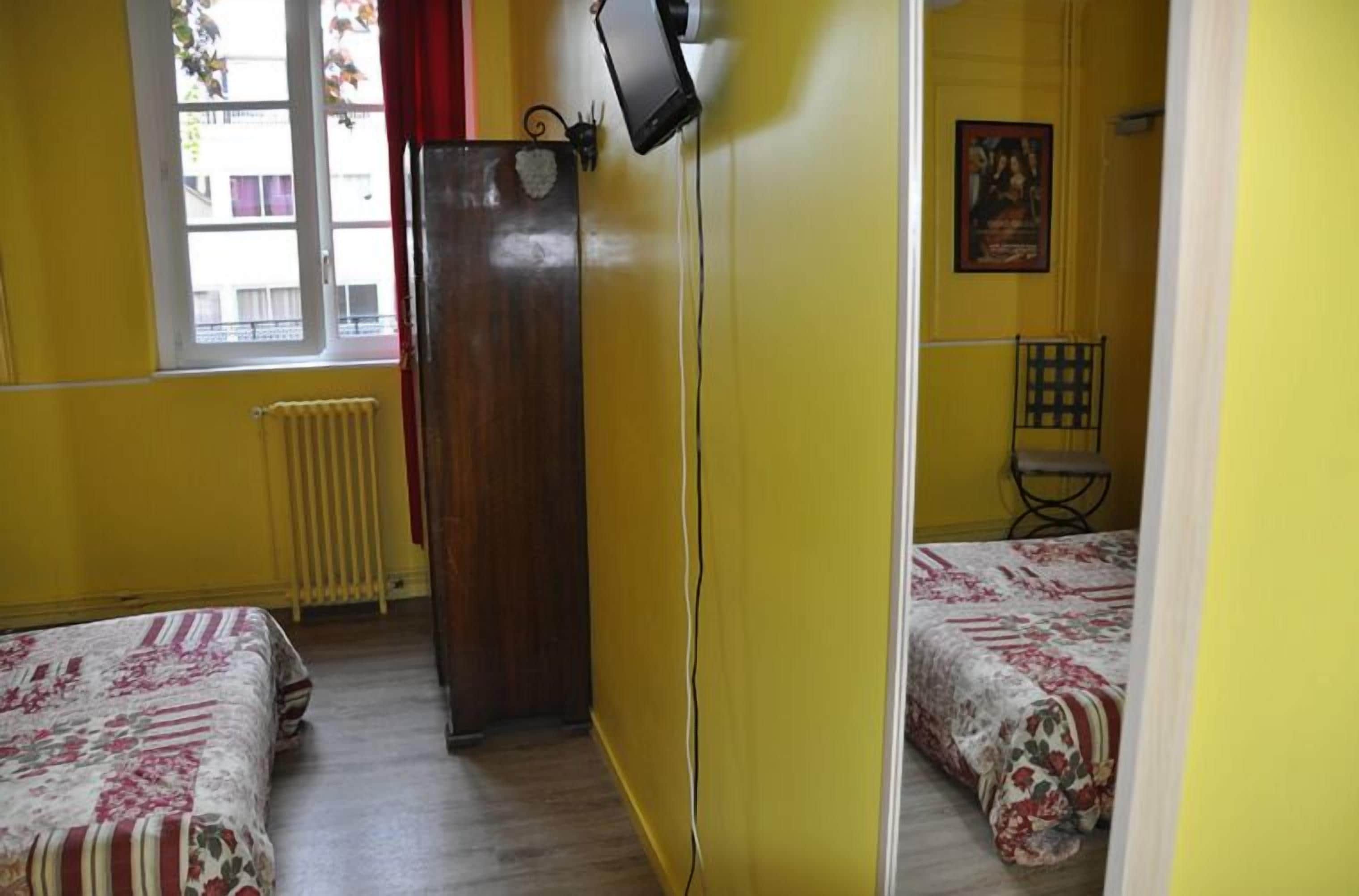 Ein Zimmer mit zwei Betten, einem Heizkörper, einem Fenster und einer Tür.