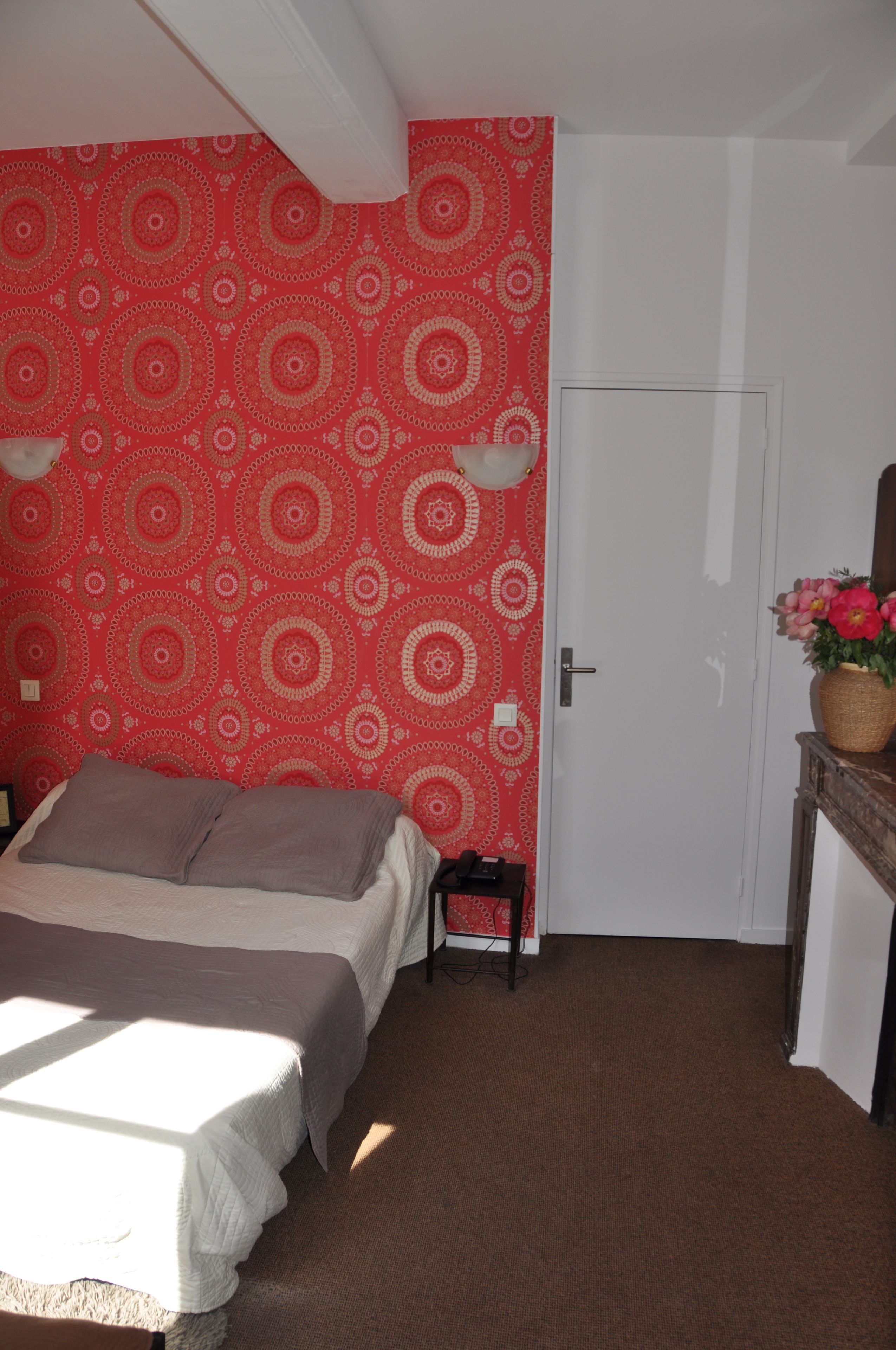 Ein Schlafzimmer mit einem Bett, einem kleinen Tisch mit Blumen und einer Tür.