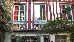 Un bâtiment traditionnel à colombages doté d’une cour intérieure aménagée avec des espaces de détente en plein air et des plantes en pot.