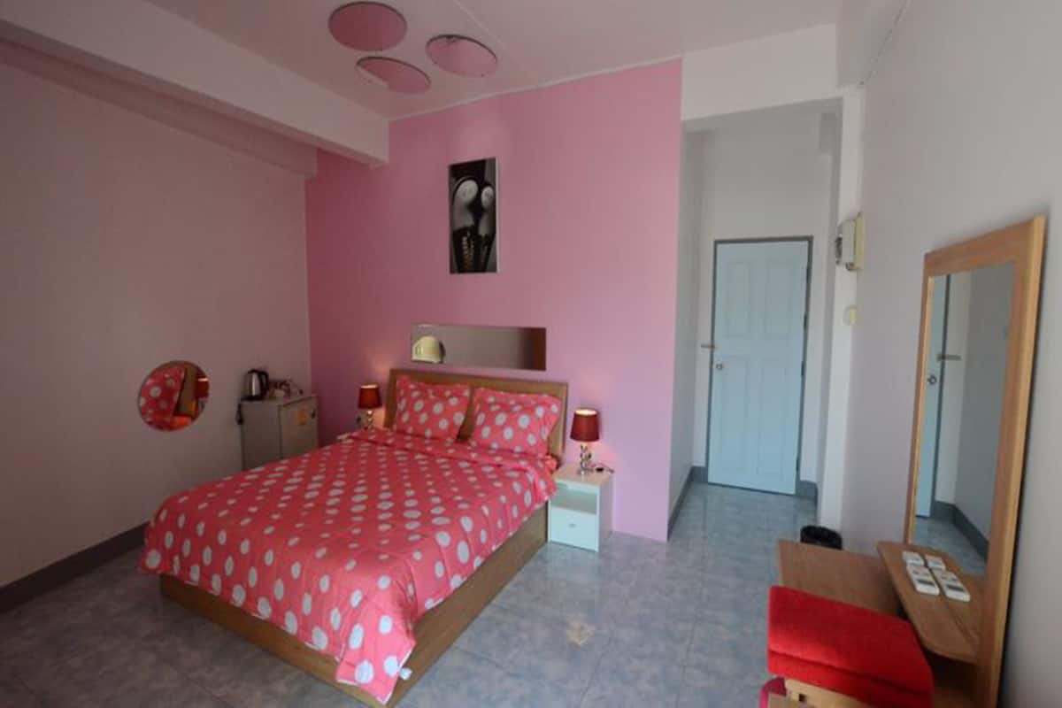 A bedroom with a bed, bedside tables, a mirror, and a door.