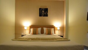 A hotel room with a large bed, two bedside lamps, and a wall-mounted artwork. - Bua Khao Paradise (Pattaya)
