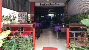 The interior of Buakht Paradise Restaurant with tables and chairs, a ceiling fan, and a welcome mat. - Bua Khao Paradise (Pattaya)