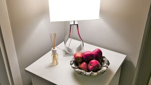 A white table with a bowl of red apples and a bottle of reed diffuser. - Residenza Maiano (Florence)