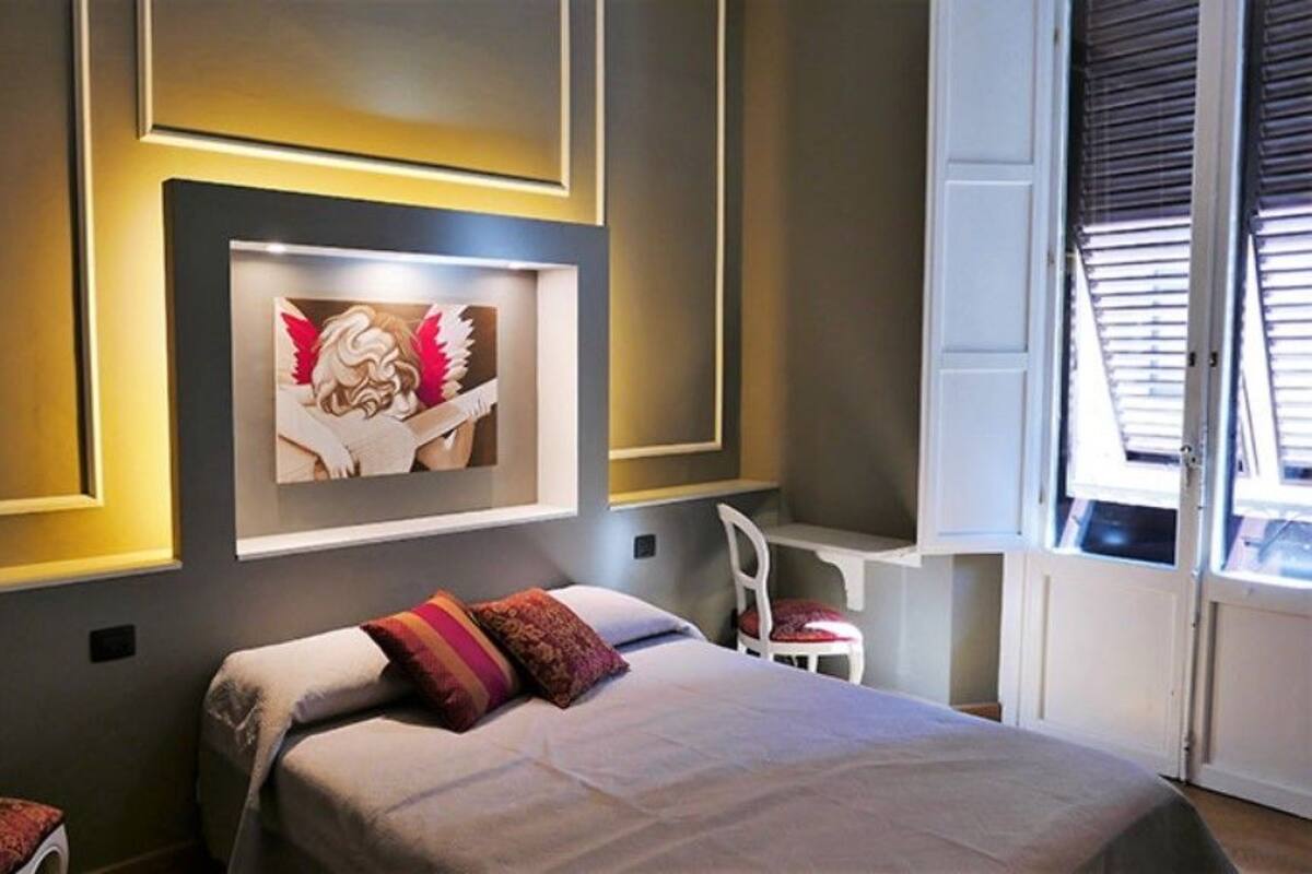A modern bedroom with a bed, a desk, and a window with blinds.