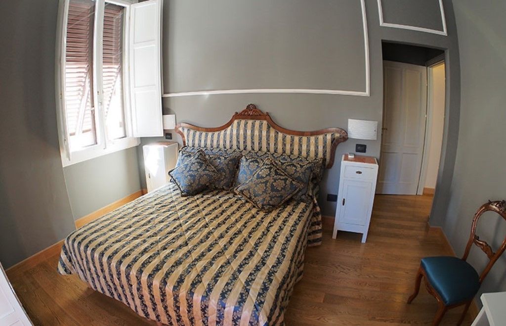 A bedroom with a bed, a nightstand, a chair, and a door.