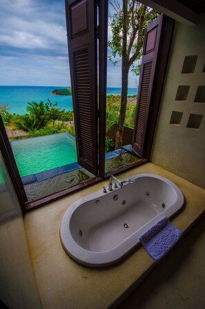 A bathroom with a bathtub and a view of a tropical beach and ocean. - Bhundhari Residence Koh Samui (Koh Samui)