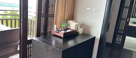 Una habitación moderna con un escritorio de madera oscura, una planta pequeña y una bandeja con botellas y vasos.