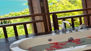 A bathroom with a bathtub, a view of the ocean, and a balcony with wooden railings. - Bhundhari Residence Koh Samui (Koh Samui)