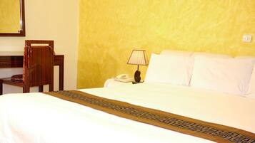 A hotel room with a bed, a bedside lamp, a telephone, and a chair.