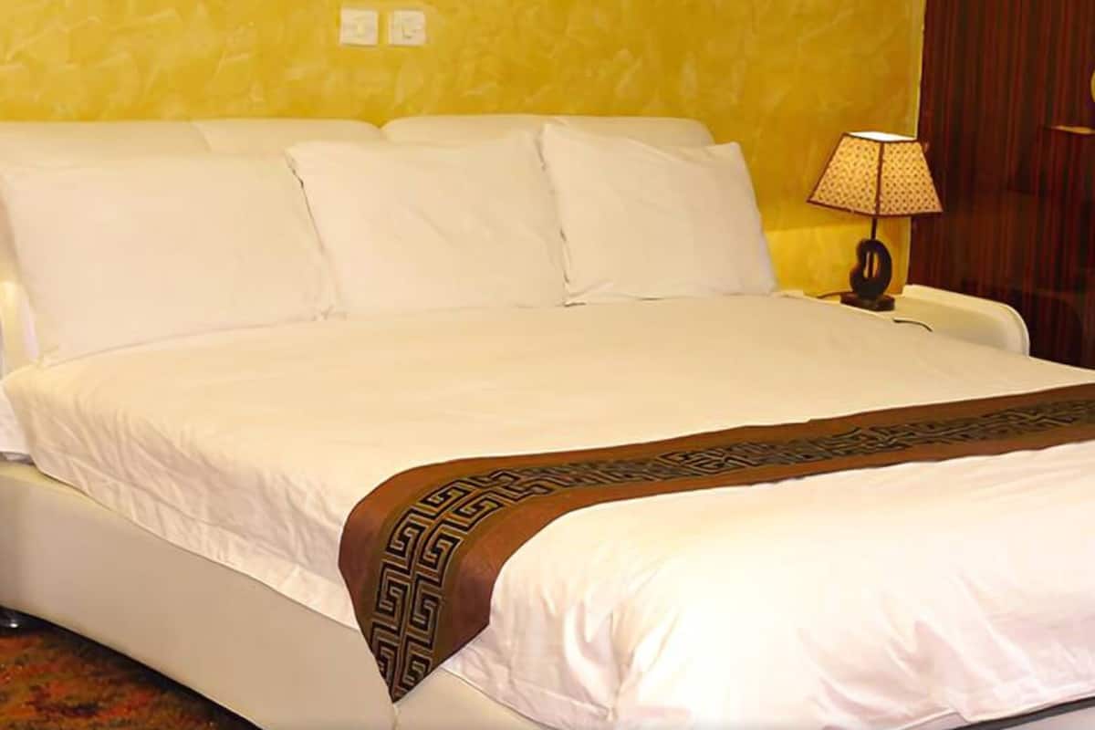Ein Hotelzimmer mit einem großen Bett, einem Holzkopfteil, einer Nachttischlampe und einer Holztür mit einem runden Griff.