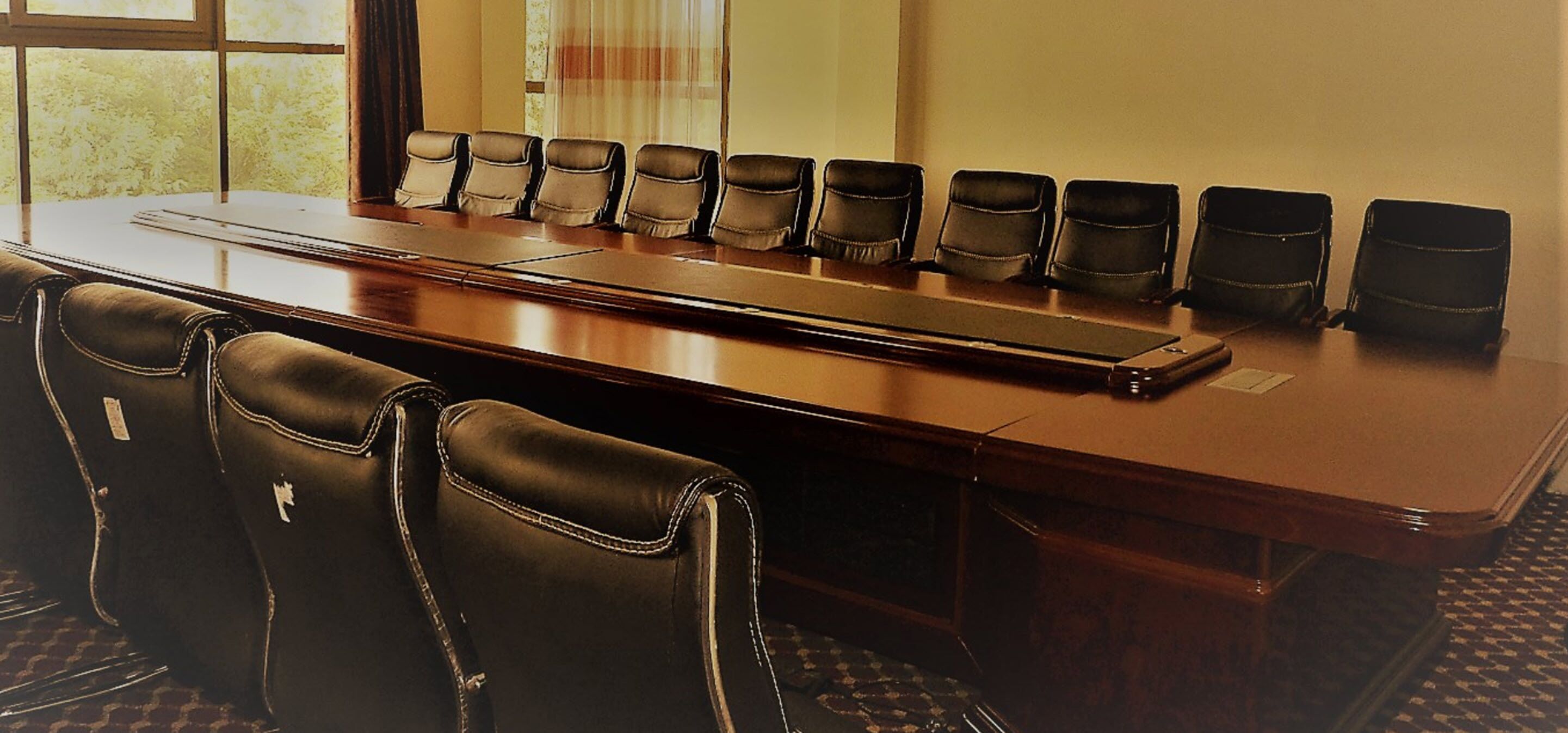 Un salón de conferencias con una larga mesa y varias sillas.