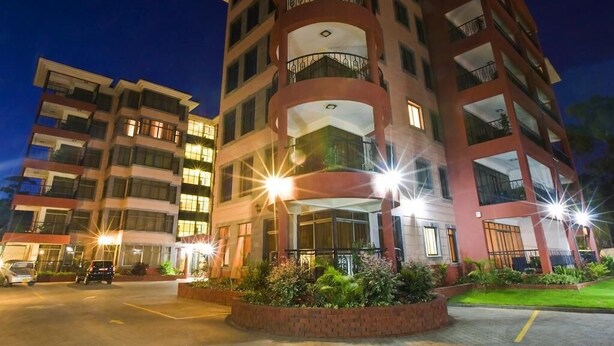A multi-story hotel with a central courtyard, balconies, and a parking area.