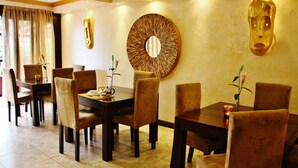 A dining area with a round table, chairs, and a wall-mounted decorative mirror.