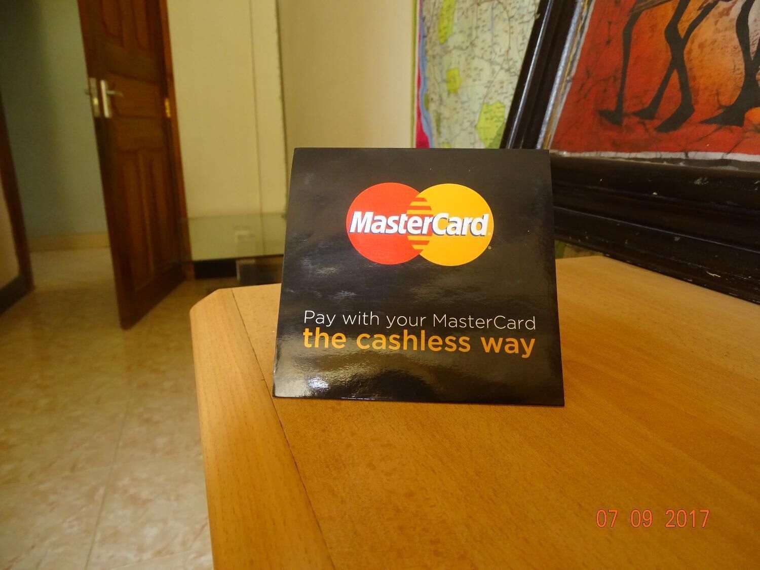 Un cartel de MasterCard sobre una mesa de madera en una habitación con un mapa en la pared.