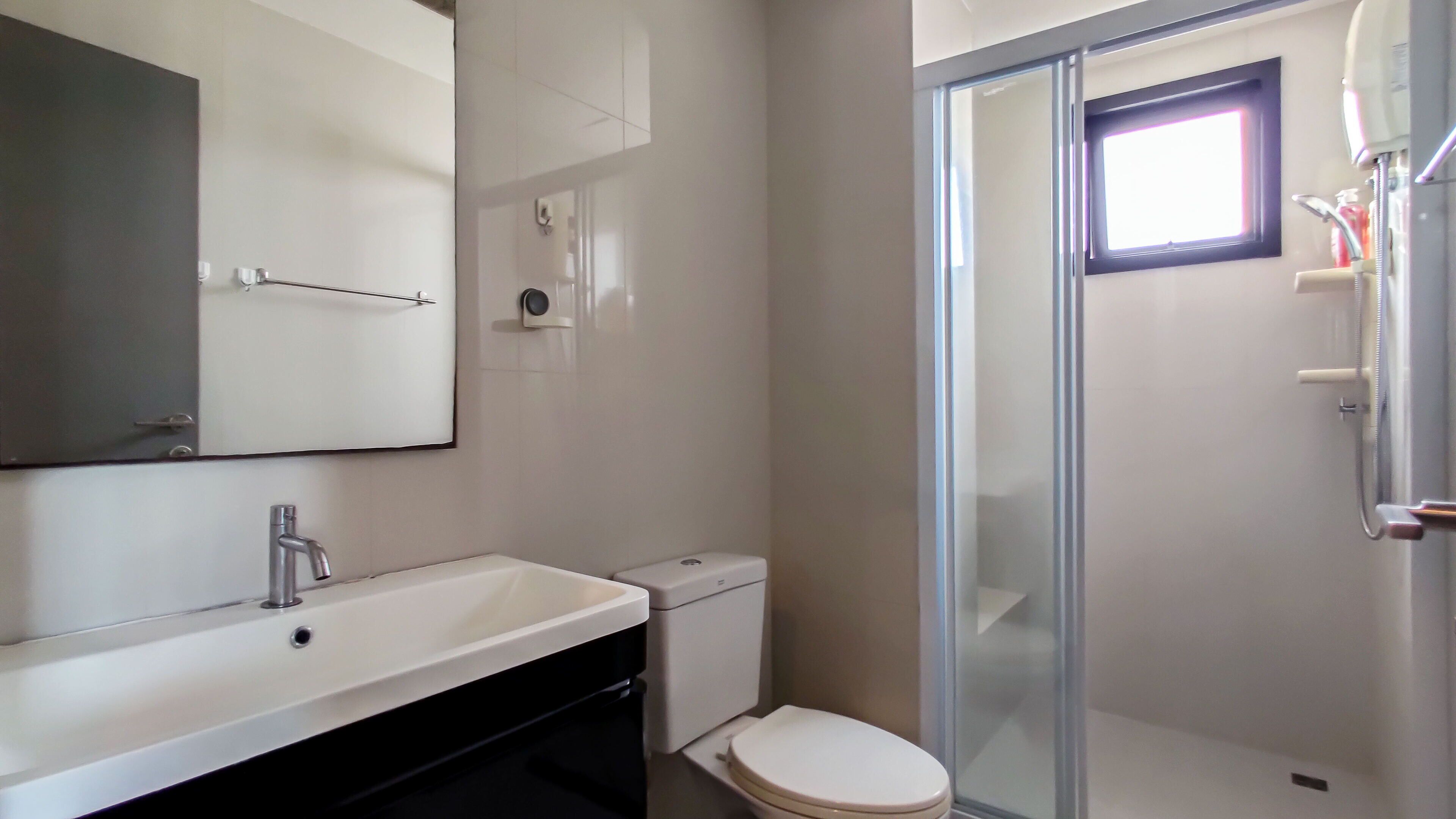 A modern bathroom with a white sink, toilet, and glass shower enclosure.
