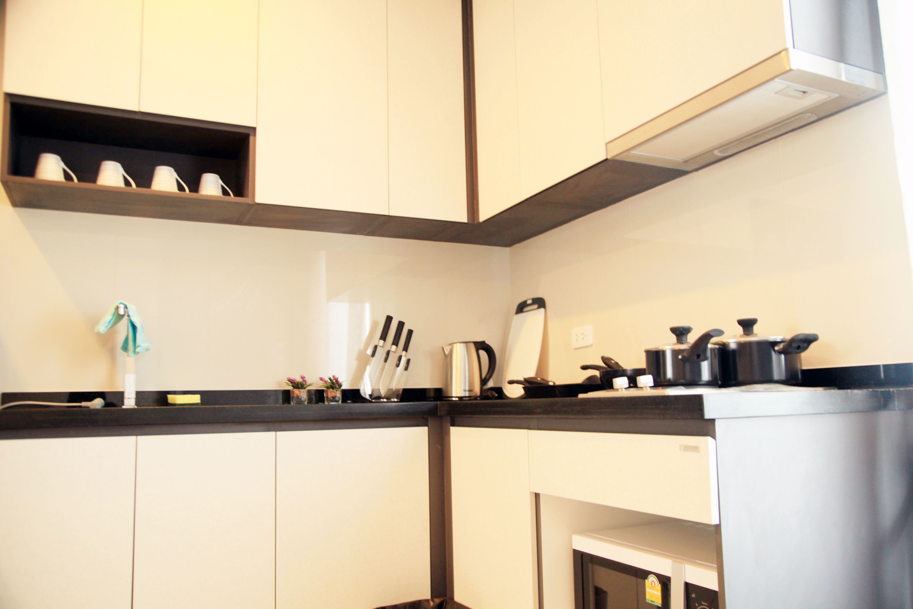 A modern kitchen with white cabinets, a black countertop, and stainless steel appliances.