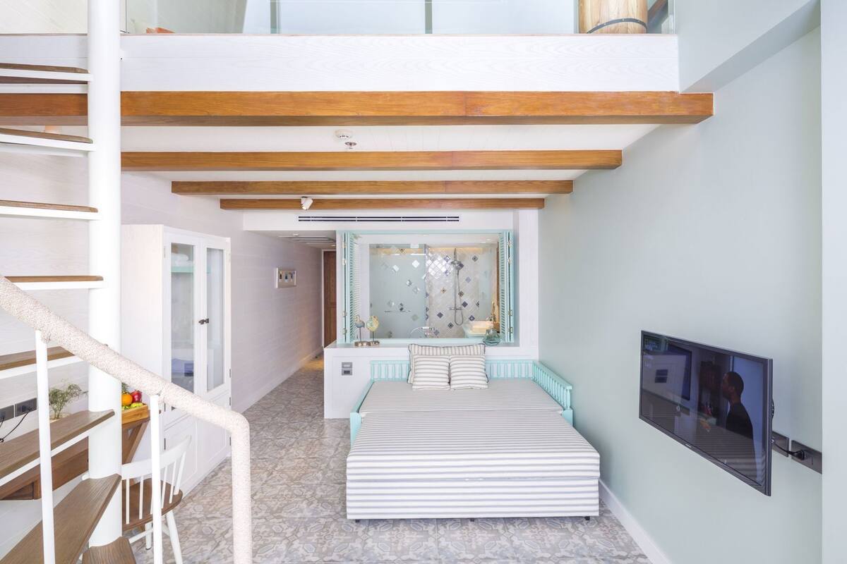 Un interior moderno con un altillo, una escalera y un televisor montado en la pared.