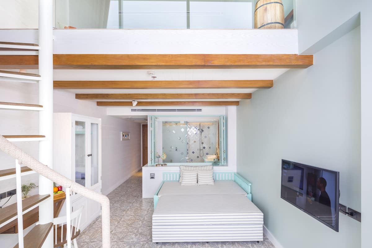 Un dormitorio moderno con una cama grande, televisión y baño con paredes de vidrio.