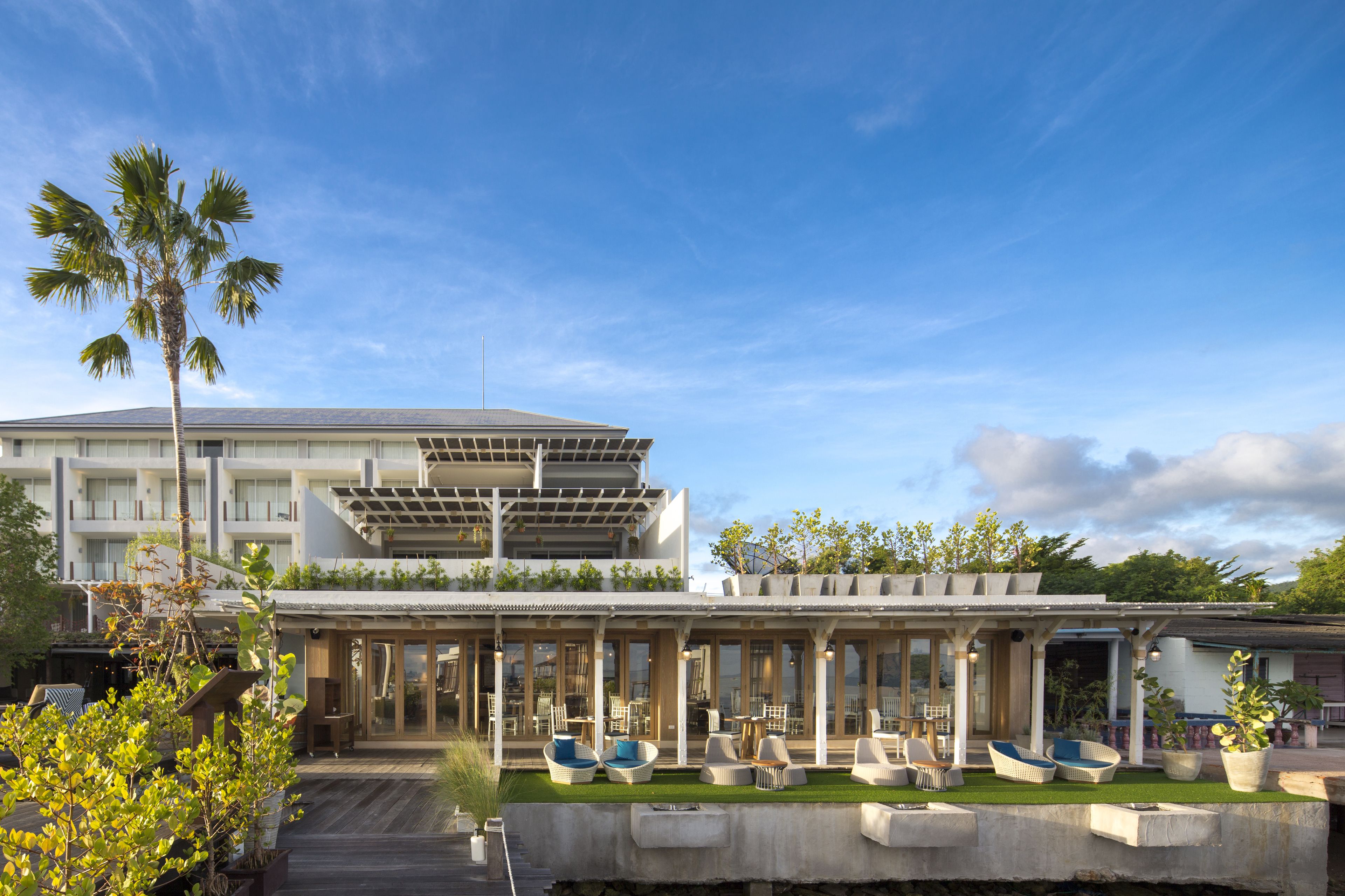 Un hotel moderno con terraza en la azotea, zona de estar al aire libre y piscina.