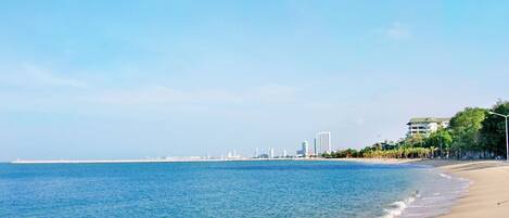 A beach with a clear view of the ocean and a distant city skyline.