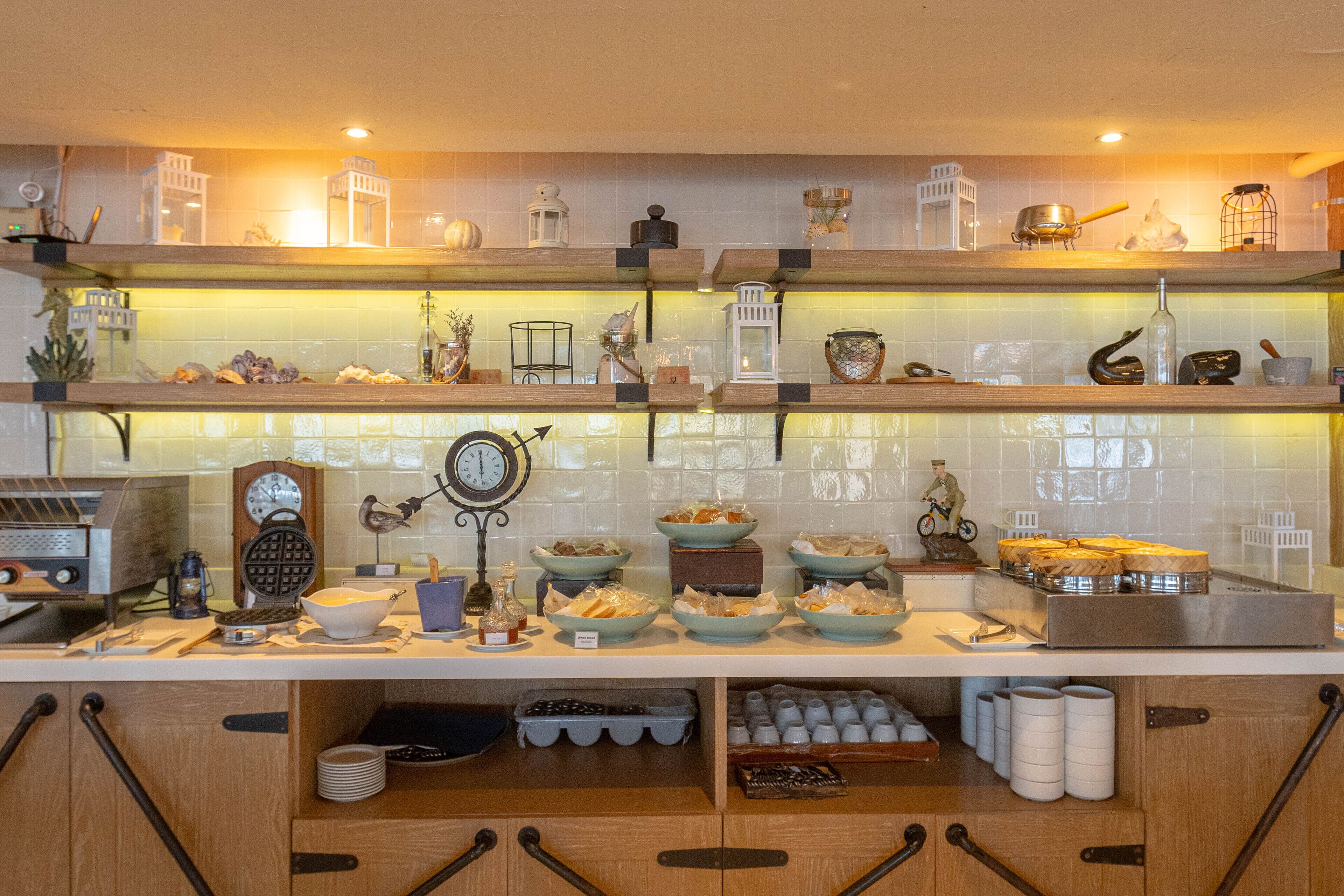 A kitchen with wooden shelves, various kitchenware, and a clock.