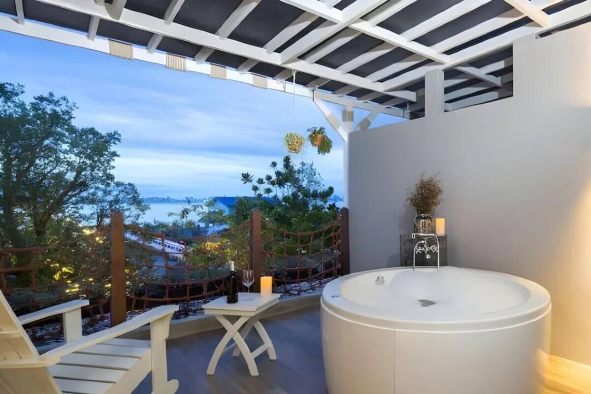 Un área de estar exterior moderna con un jacuzzi, terraza de madera y vistas a la ciudad.