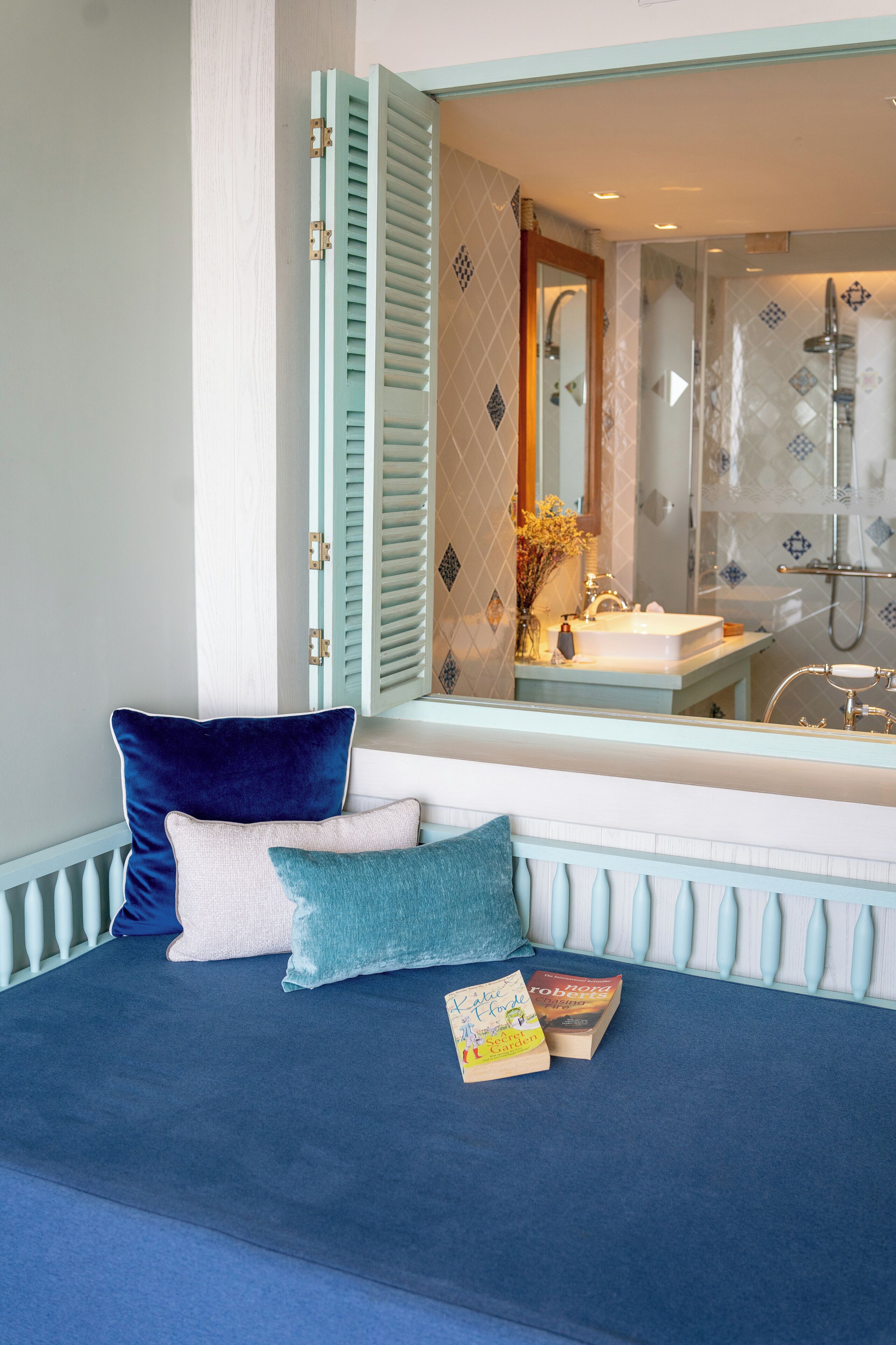 A bedroom with a bed, pillows, and a bedside table with books.