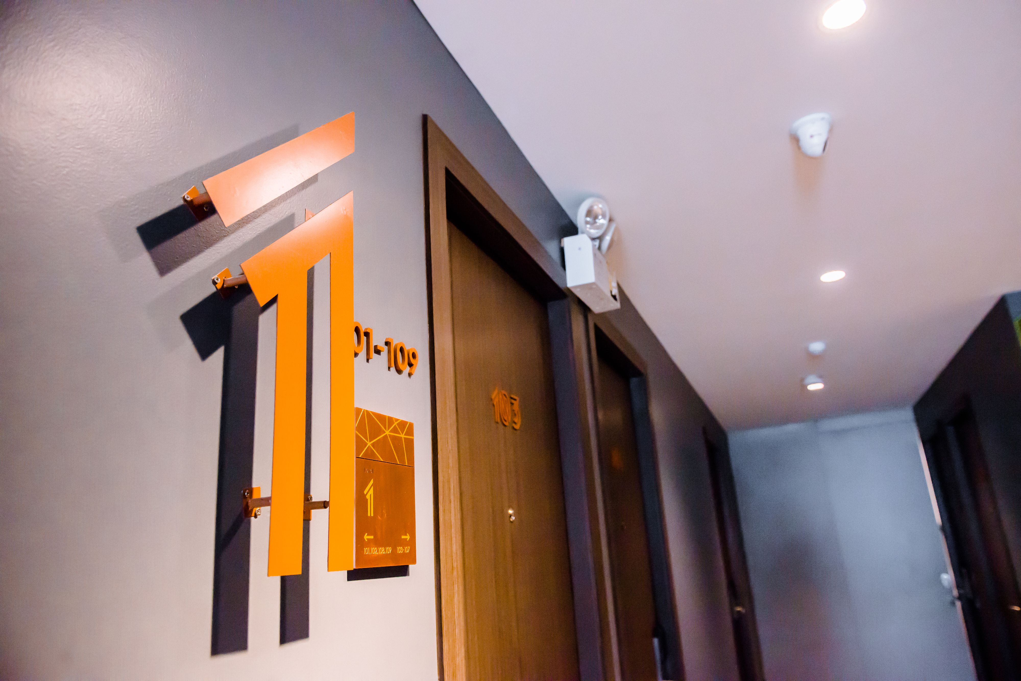 Un pasillo con una puerta de madera que tiene el número 101 y un letrero con flechas direccionales.