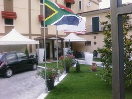 A building with a flag, a car, and outdoor seating.