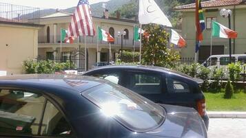A building with multiple flags, including the American flag, and parked cars in front.