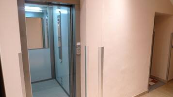 An elevator with a control panel, a glass door, and a carpeted floor.