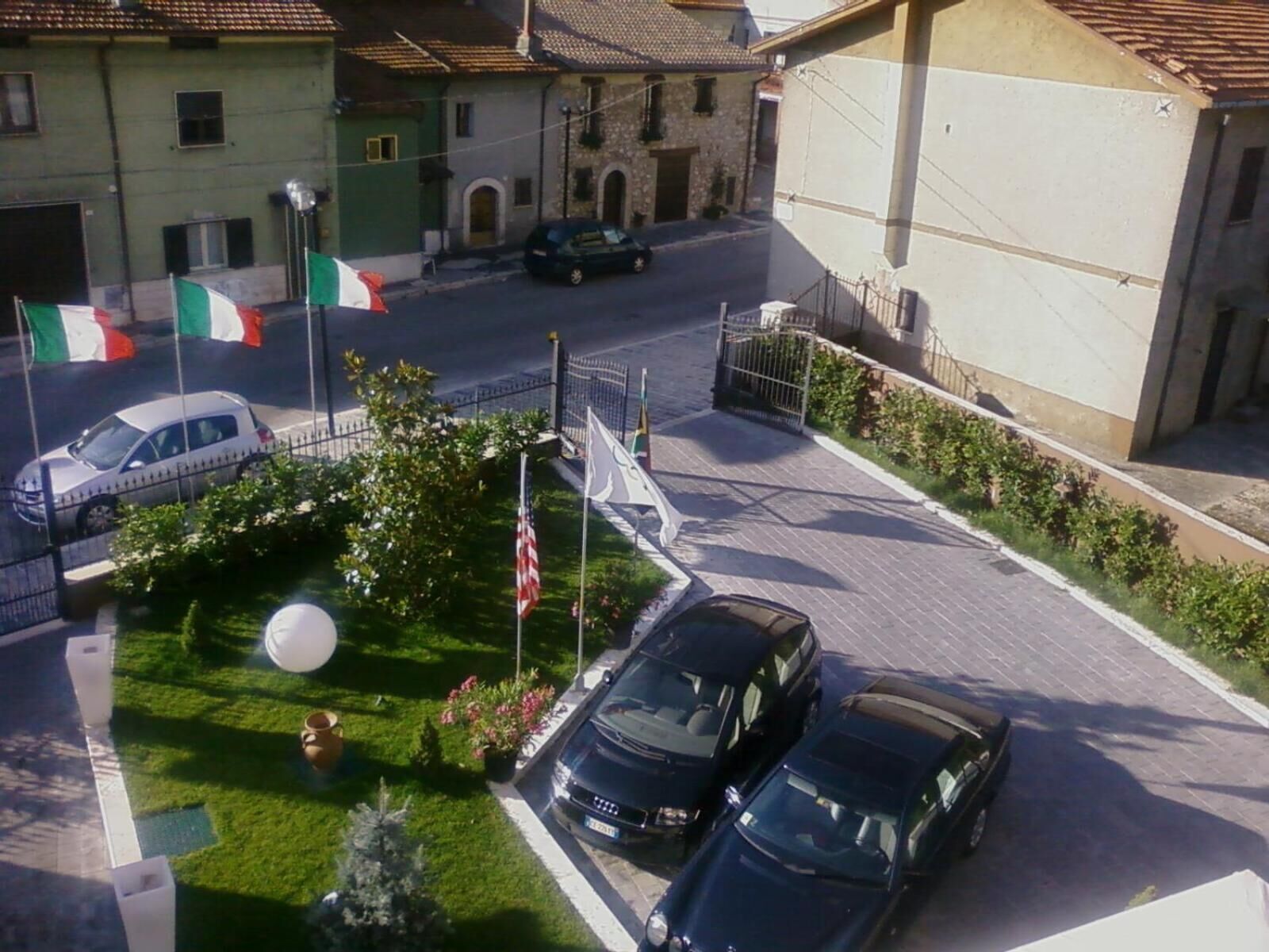 A parking area with two cars, a flag, and a flagpole.
