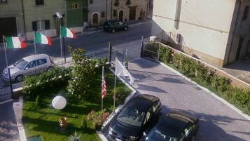 A parking area with two cars, a flag, and a flagpole.
