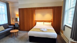 A hotel room with a bed, a sofa, a small table, and a desk. - Russell Hotel (Royal Tunbridge Wells)