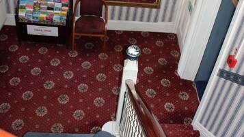 Staircase with a mirror, chair, and framed picture, set against a backdrop of vertical stripes.